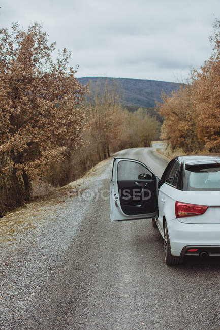 Carro com porta do motorista aberta estacionada na estrada rural de outono — Fotografia de Stock