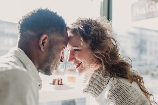 Cheerful couple in sweaters bonding by window — Stock Photo