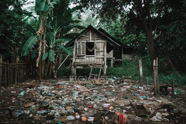 Cumulo di spazzatura che giace vicino casa di legno nel villaggio asiatico . — Foto stock