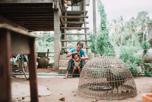 Laos, 4000 inseln: mama sitzt auf treppe und kämmt tochter — Stockfoto