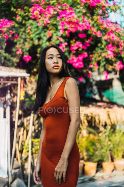 Serena mulher em vestido vermelho posando na rua — Fotografia de Stock