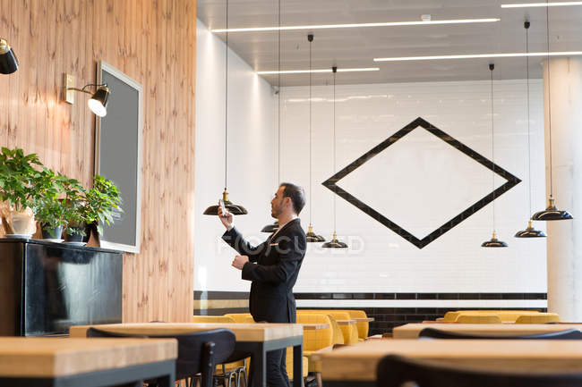 Вид сбоку человека, стоящего и просматривающего смартфон за столом в кафе . — стоковое фото
