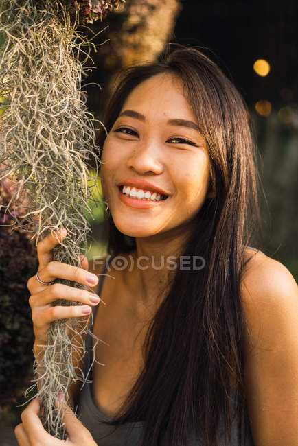 Mujer alegre sosteniendo hierba seca y sonriendo a la cámara - foto de stock