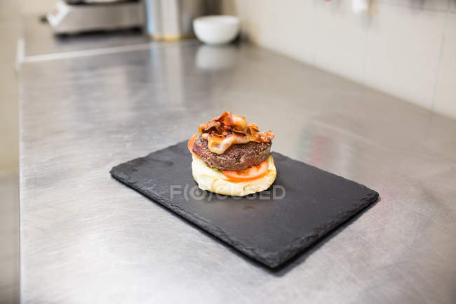 Burger inachevé sur assiette à table dans la cuisine du restaurant — Photo de stock