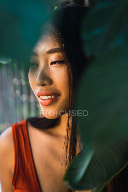 Portrait of smiling woman behind green leaves — Stock Photo