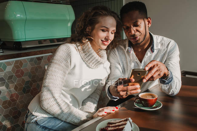 Paar surft mit Smartphone am Cafétisch — Stockfoto