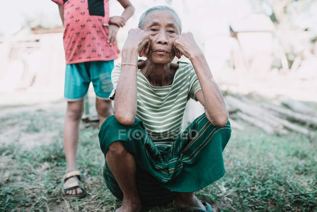 Nong khiaw, laos: ältere Frau sitzt auf Gras und blickt in die Kamera — Stockfoto