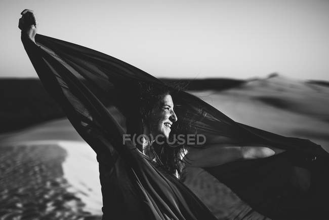 Donna allegra in posa con tessuto su dune di sabbia — Foto stock