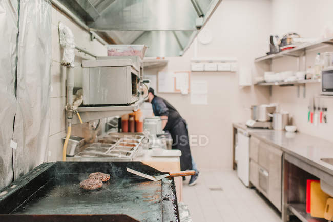 Vue latérale du chef travaillant sur la cuisine dans le restaurant . — Photo de stock