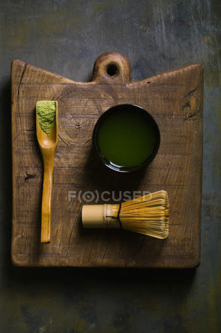 Matcha chá em colher por batedor de bambu com xícara na placa de corte — Fotografia de Stock