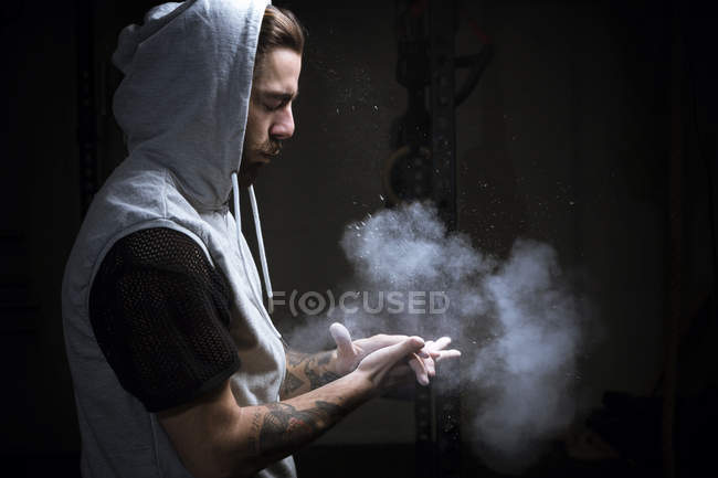 Man clapping hands with chalk powder over dark background — Stock Photo