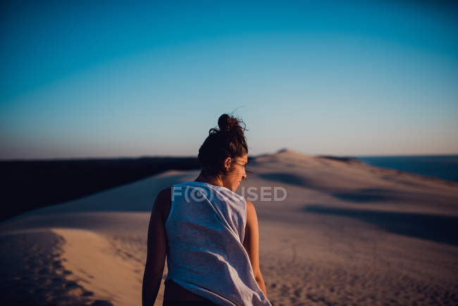 Visão traseira da mulher morena em pé na areia e olhando para longe — Fotografia de Stock