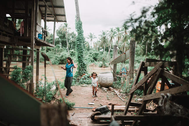 LAOS, 4000 ILHAS ÁREA: Mulher e menina bonito de pé perto de casa na rua da aldeia . — Fotografia de Stock