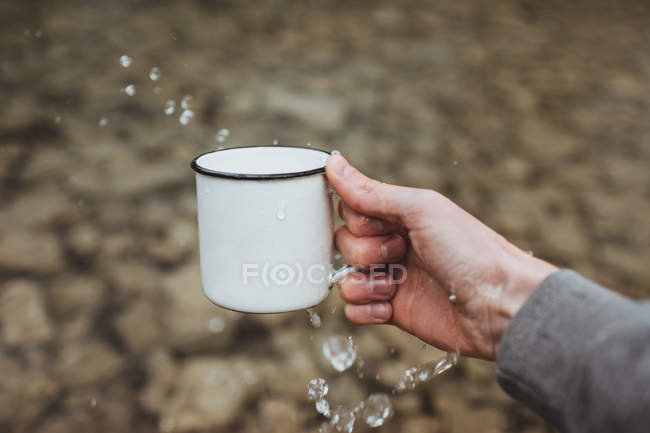 Coltiva mano spruzzando acqua dalla tazza di metallo — Foto stock