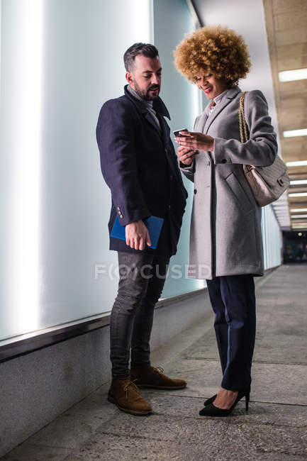 Стильный мужчина смотрит на женщину, просматривающую смартфон — стоковое фото
