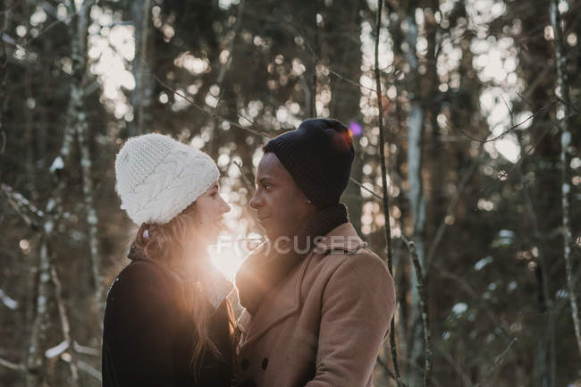 Чувственная пара, соединяющаяся в зимнем лесу над лучами заката — стоковое фото