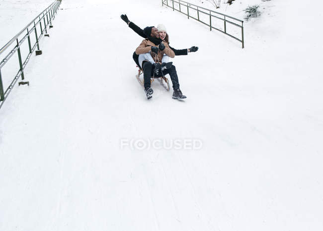 Casal equitação trenó no monte nevado — Fotografia de Stock