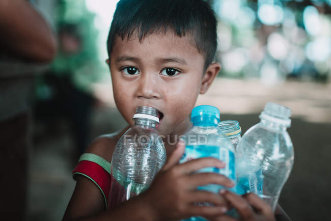 LAOS, 4000 ILHAS ÁREA: Menino com garrafas de plástico olhando para a câmera — Fotografia de Stock