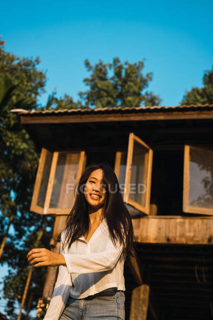 Pretty woman posing near house and looking at camera — Stock Photo