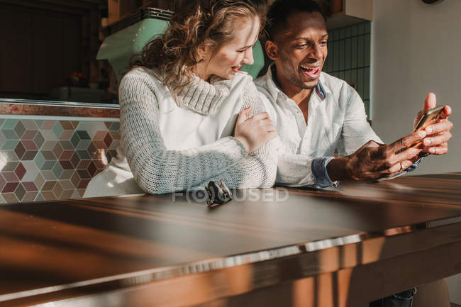 Весела пара зі смартфоном на побаченні в кафе — стокове фото