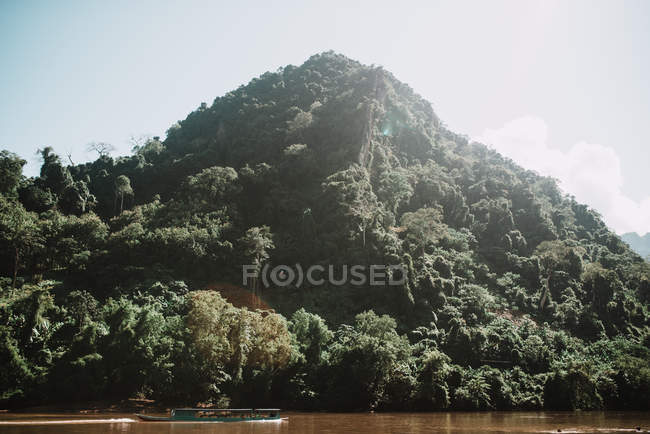 Canoe floating on river along green mountain — Stock Photo