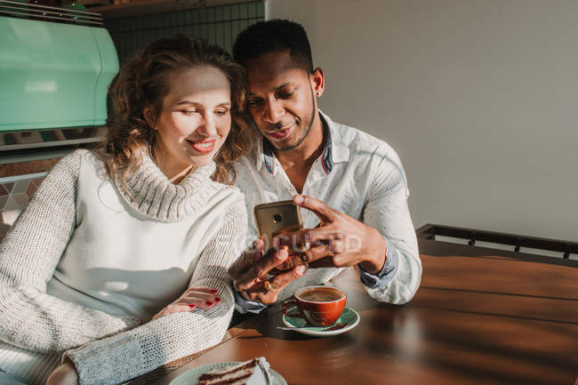 Casal de ligação usando smartphone no café — Fotografia de Stock