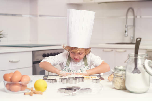 Lindo niño alegre balanceo amasar en el mostrador de cocina - foto de stock