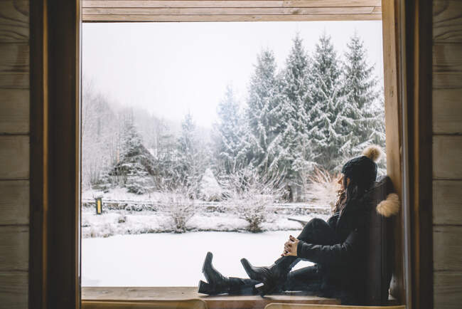 Jolie fille dans la fenêtre de la cabine regardant le paysage enneigé. — Photo de stock