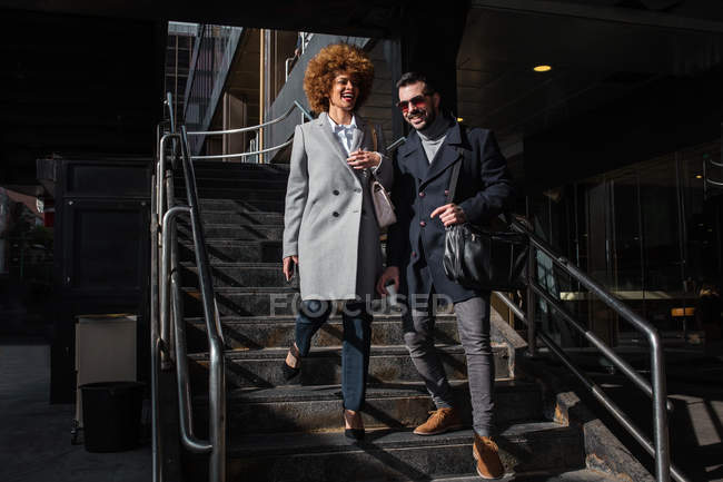 Fröhliches stylisches Paar geht die Treppe hinunter und lacht zusammen. — Stockfoto