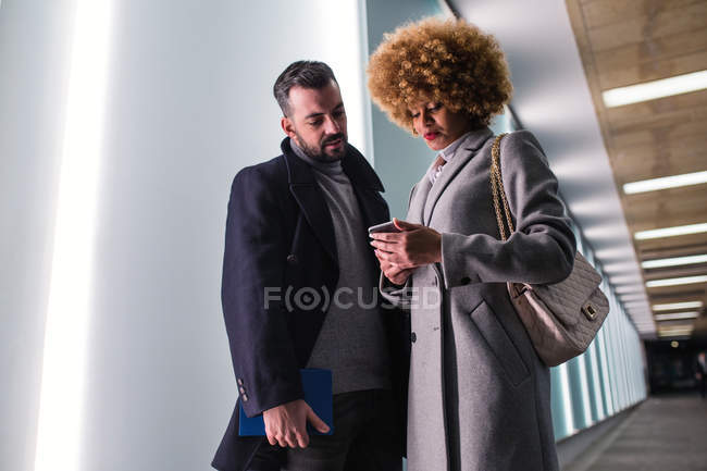 Homem elegante olhando para mulher encaracolado navegação smartphone — Fotografia de Stock