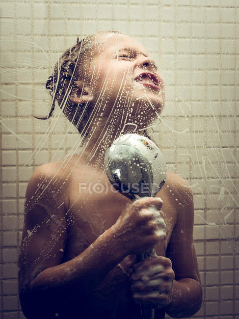 Young boy singing to shower while washing in bathroom. — Stock Photo