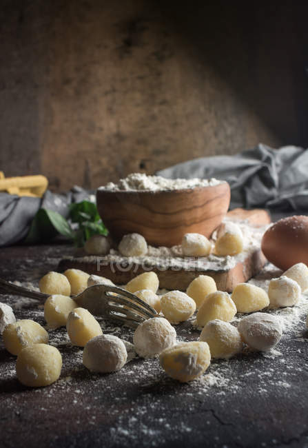 Natura morta di gnocchi crudi e ingredienti in tavola — Foto stock