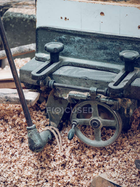 Máquina de carpintería de metal negro y esquejes de madera en taller . - foto de stock