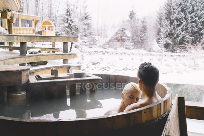 Casal abraçando e relaxando na banheira de mergulho no inverno — Fotografia de Stock