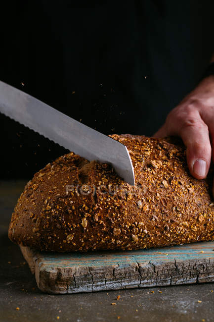Couper des tranches de pain aux mains masculines — Photo de stock