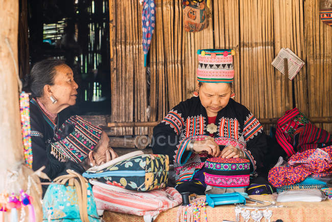 CHIANG RAI, THAILAND- FEVEREIRO 12, 2018: Mulheres idosas sentadas na rua e elaborando roupas tradicionais . — Fotografia de Stock