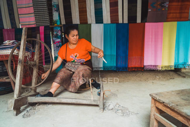 LAOS- FEBRERO 18, 2018: Mujer sonriente trabajando con hilandero de tela - foto de stock