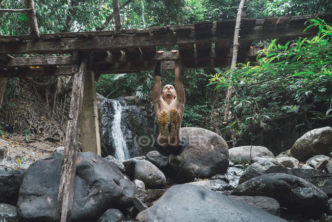 Man hanging on old wooden bridge — Stock Photo