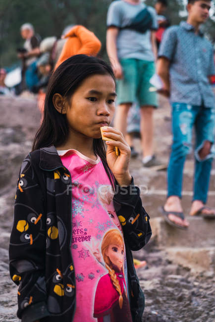 18. Februar 2018: Nachdenkliches junges Mädchen steht und isst. — Stockfoto