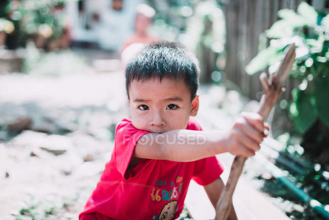 Laos, luang prabang: Kind sitzt auf dem Boden und spielt mit Stock — Stockfoto