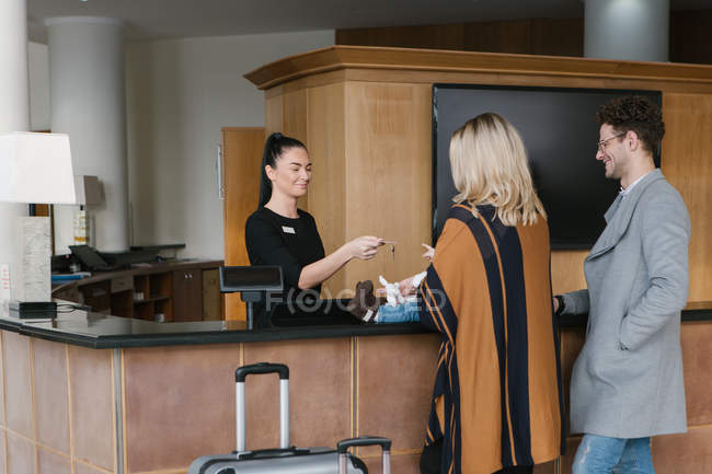 Trabalhador da recepção dando a chave à família no hotel — Fotografia de Stock