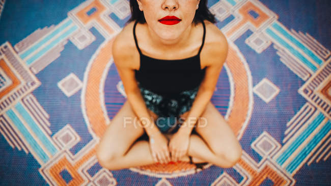 De arriba mujer de la cosecha con los labios rojos sentados en la alfombra . - foto de stock