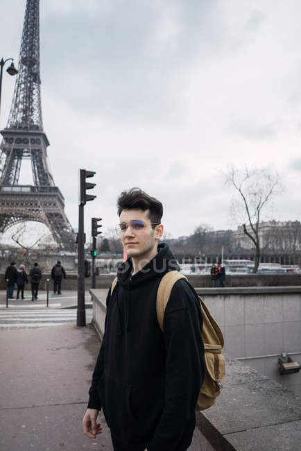 Jovem com mochila em pé no fundo da torre Eiffel
. — Fotografia de Stock