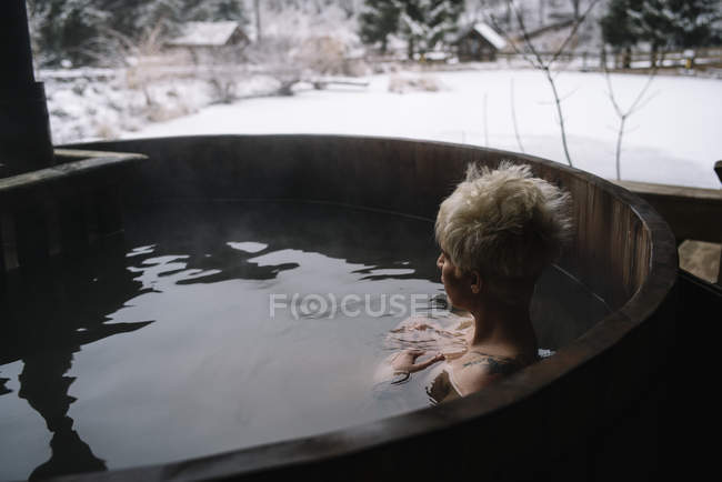 Вид збоку на блондинку з коротким волоссям, що плаває на вулиці, пориньте у ванну взимку . — стокове фото