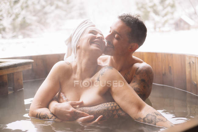 Sinnlich tätowiertes Paar, das sich im Winter in der Badewanne umarmt. — Stockfoto