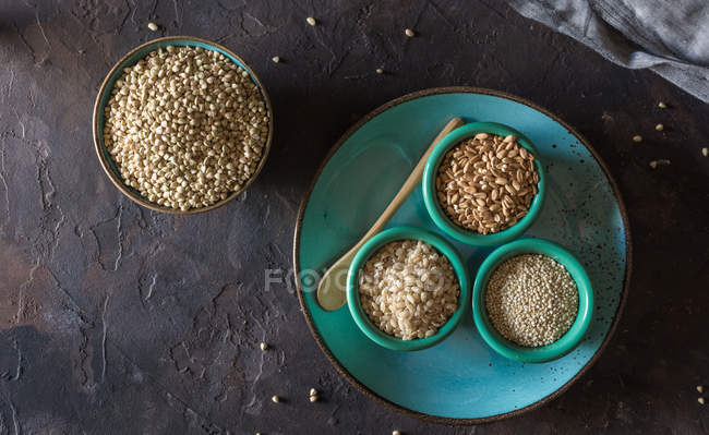 Directamente por encima de la vista de cuencos llenos de trigo sarraceno y otros cereales copos de trigo . - foto de stock