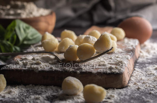 Vue rapprochée des gnocchis crus sur une planche en bois — Photo de stock