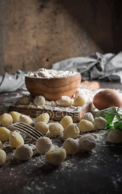 Nature morte des gnocchis crus et des ingrédients sur la table — Photo de stock