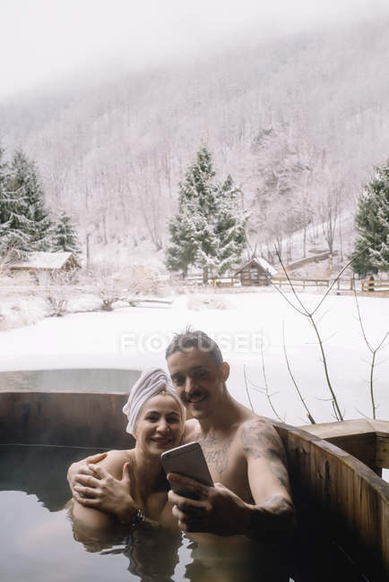 Casal sentado na banheira de mergulho no inverno — Fotografia de Stock