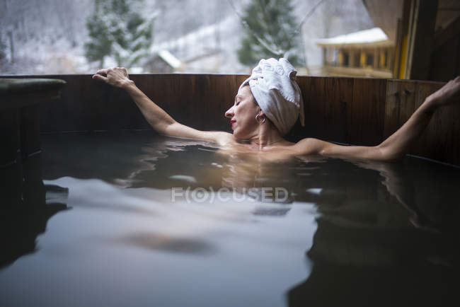 Alegre mujer en topless en la bañera de inmersión exterior relajante en la naturaleza . - foto de stock